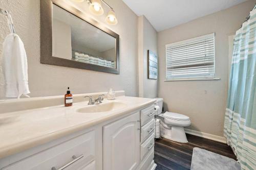 a bathroom with a sink and a toilet and a mirror at Large South Houston gem with covered patio seating in Pearland