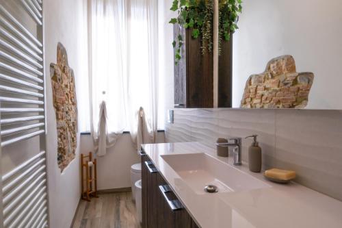 baño blanco con lavabo y ventana en Dimora Pietra Blu, en Pisa