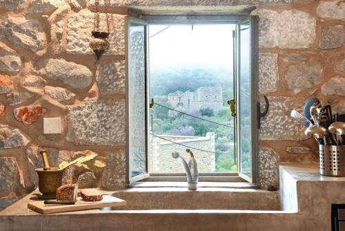 una cocina con paredes de piedra, ventana y fregadero en Lagia ZeN Residence, en Láyia