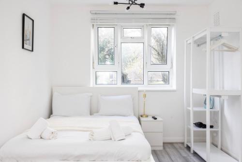 ein weißes Schlafzimmer mit einem Bett und zwei Fenstern in der Unterkunft Modern 2 Bedroom Apartment Brixton Station in London