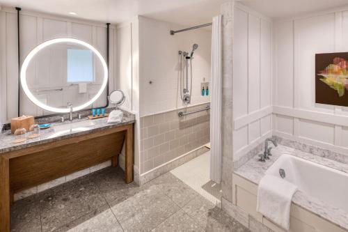 ein Badezimmer mit einer Badewanne, einem Waschbecken und einem Spiegel in der Unterkunft Ocean Bungalows at Turtle Bay Resort in Kahuku
