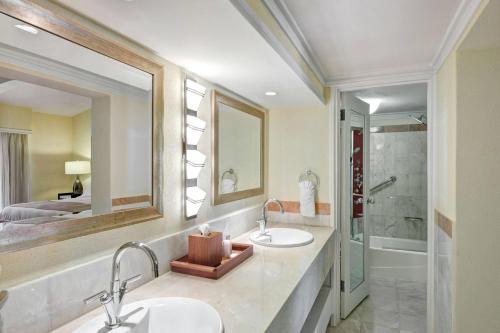 a bathroom with two sinks and a mirror and a tub at The House by Elegant Hotels - All-Inclusive, Adults Only in Saint James