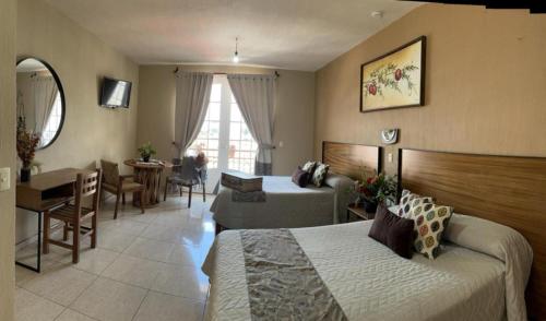 a hotel room with two beds and a dining room at Hotel el Leñador in Mazamitla