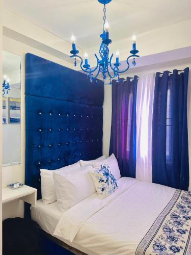 a bed with a blue head board and a chandelier at CasadeIsabel: Elegant 2BR n Cebu/Washing/Netflix in Cebu City