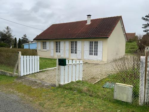 une petite maison blanche avec une clôture blanche dans l'établissement LES BAINS, à Barneville-Carteret