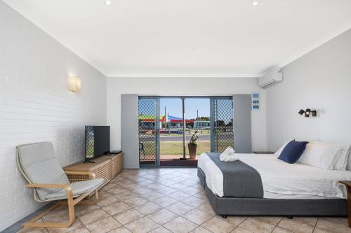 a bedroom with a bed and a chair and a television at Windsurfer Beach Studio in Lancelin