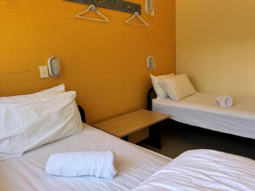 two beds in a room with a yellow wall at Windsurfer beach Chalet 1 in Lancelin