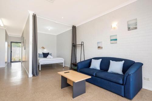 a living room with a blue couch and a table at Windsurfer Beach Chalet 3 in Lancelin