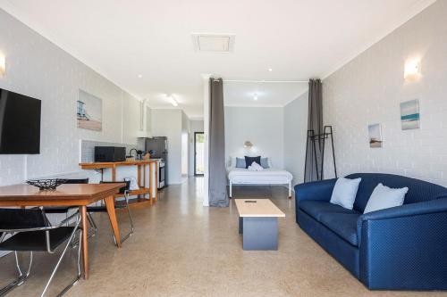 a living room with a blue couch and a kitchen at Windsurfer Beach Chalet 5 in Lancelin