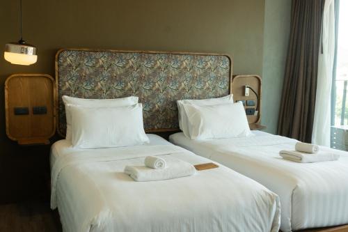 two beds in a hotel room with towels on them at Seamira House Huahin in Hua Hin
