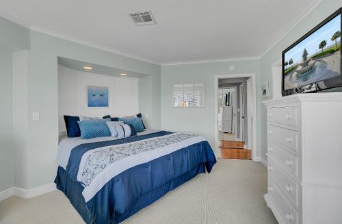 a white bedroom with a blue bed and a tv at 304 E Port by AvantStay Rooftop Deck Close to Beach in Isle of Palms