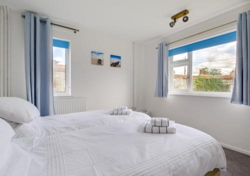 a white bedroom with two beds and two windows at Kenada in Docking