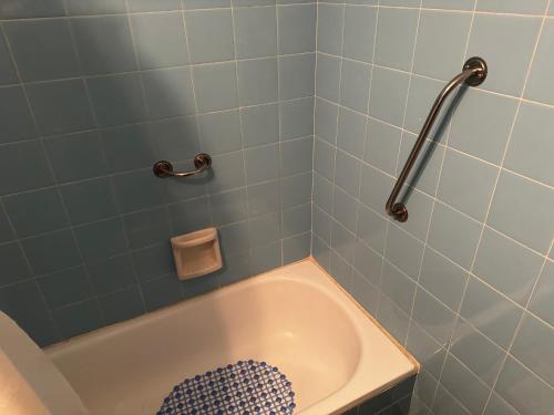 y baño con bañera y pared de azulejos azules. en Departamento 2 ambientes en olivos -mínimo 2 noches in 