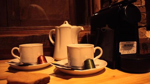 two cups and saucers sitting on a wooden table at Estancia San Alberto Lodge in Uspallata