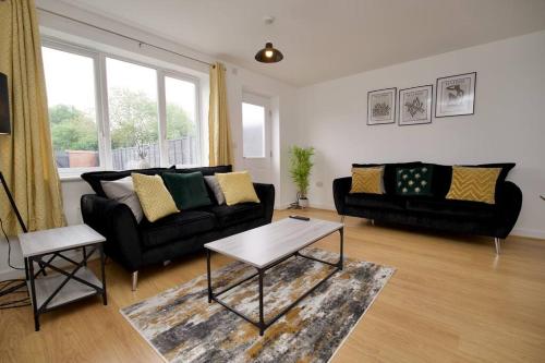 a living room with a black couch and a table at Highley's Nest - Fully Furnished Gem, Free Private Parking, Sky TV & Netflix in Coventry