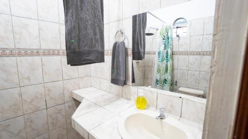 La salle de bains blanche est pourvue d'un lavabo et d'un miroir. dans l'établissement Casita en el centro de la ciudad, à Iquitos