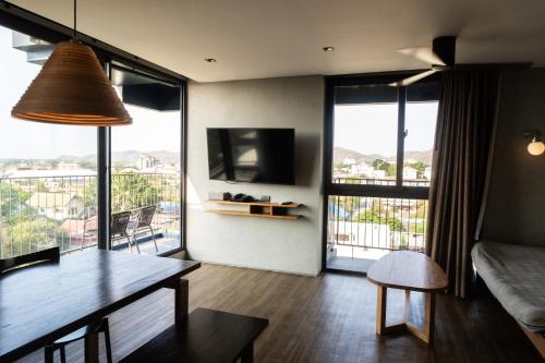 a living room with a table and a couch and some windows at Seamira House Huahin in Hua Hin