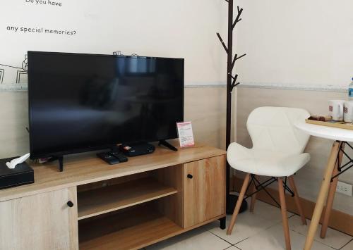 TV de pantalla plana en un soporte de madera con silla blanca en 儷福花園山莊Lifu Garden Inn, en Hualing