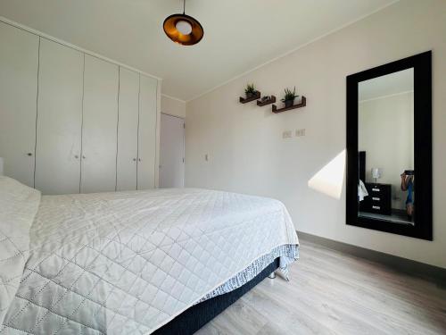 een slaapkamer met een wit bed en een spiegel bij HC San Isidro Apartment in Lima