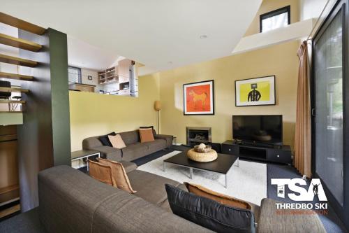 a living room with a couch and a tv at Oberdere 2 in Thredbo