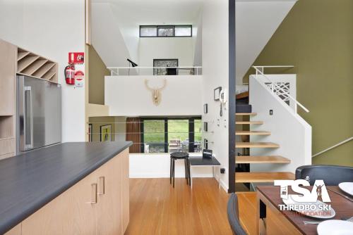 a kitchen and dining room with a staircase in a house at Oberdere 2 in Thredbo