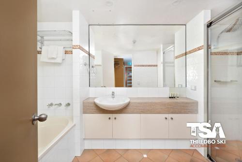 a white bathroom with a sink and a mirror at Oberdere 2 in Thredbo