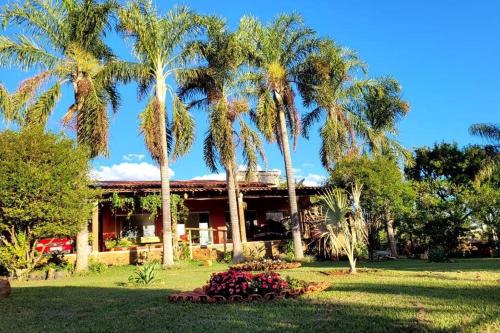 a house with palm trees in front of a yard at Rancho Encanto de Furnas - Guapé in Guapé