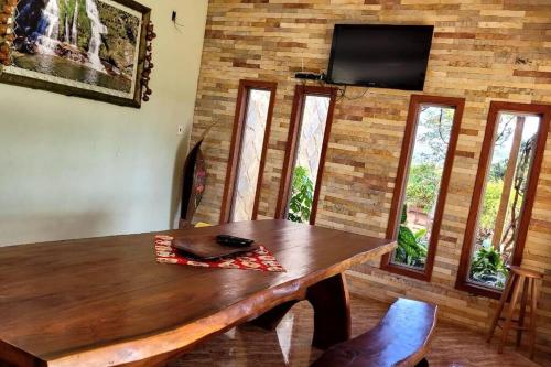 a dining room with a wooden table and a flat screen tv at Rancho Encanto de Furnas - Guapé in Guapé