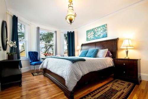 een slaapkamer met een groot bed en een blauwe stoel bij The Golden Parlor- Historic Victorian, Hot Tub in Grass Valley