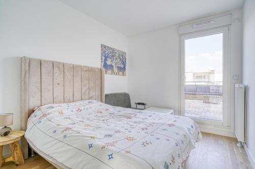 een slaapkamer met een bed en een raam bij Grand appartement avec belle vue Paris in Rueil-Malmaison
