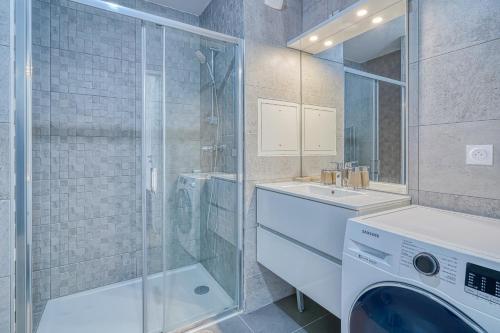 een badkamer met een wasmachine en een wastafel bij Grand appartement avec belle vue Paris in Rueil-Malmaison