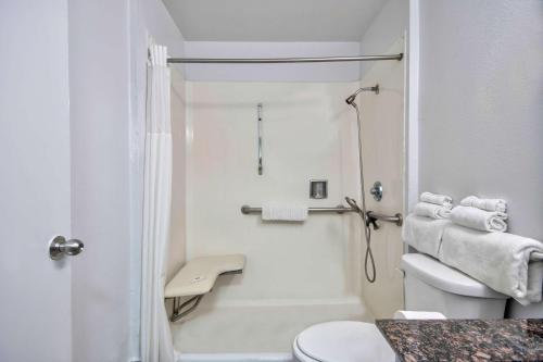 a white bathroom with a shower and a toilet at Studio 6 Suites San Bernardino, CA in San Bernardino