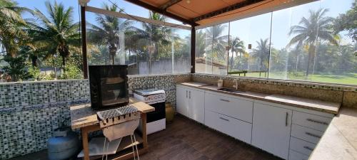 an outdoor kitchen with a large window with palm trees at Maravilhoso Recanto Santa Rosa in Guarapari