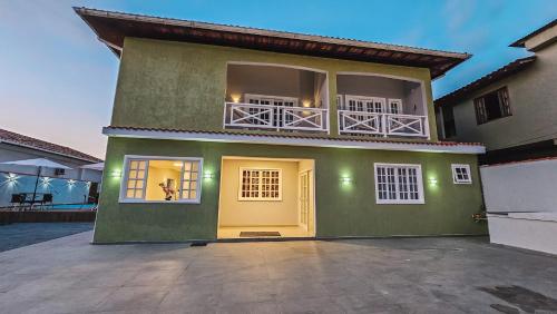 a green house with a yellow door and a balcony at Pousada Recanto Praiano in Angra dos Reis