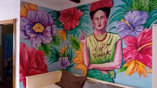 une fresque d'un homme sur un mur avec des fleurs dans l'établissement Frida Almuñecar, à Almuñécar
