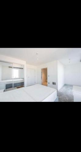 ein weißes Schlafzimmer mit einem großen Bett und einem Fenster in der Unterkunft Amazing Apartment in Harlow