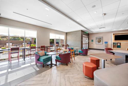 a dining room with tables and chairs and windows at Home2 Suites By Hilton San Bernardino in San Bernardino