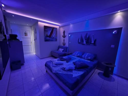 Cette chambre bleue comprend un lit et un canapé. dans l'établissement Le Voilier - Élégant studio vue sur mer avec piscine, à Les Trois-Îlets