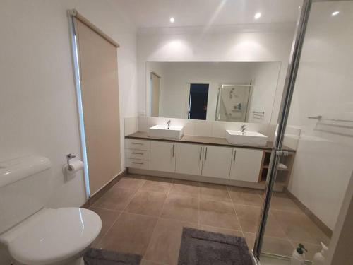 a bathroom with two sinks and a toilet and a mirror at Large townhouse direct access to beautiful beach in Safety Beach