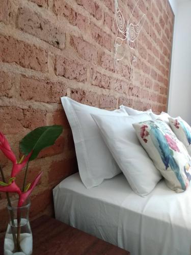 a group of pillows on a bed against a brick wall at Pousada Vila Guyrá in Florianópolis