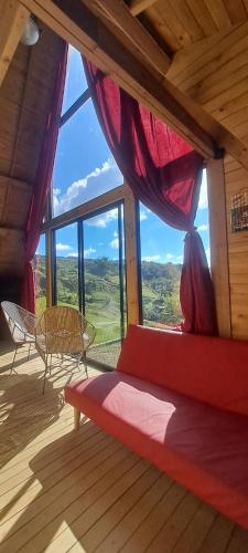 a room with a red bed and a large window at Chalet de Liz in Guatapé