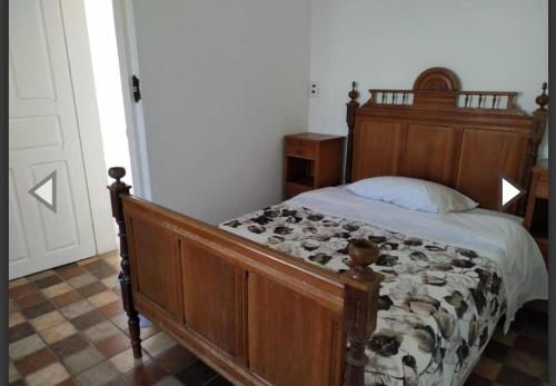 a bed in a bedroom with a wooden bed frame at Suítes da Praça Tiradentes in Tiradentes