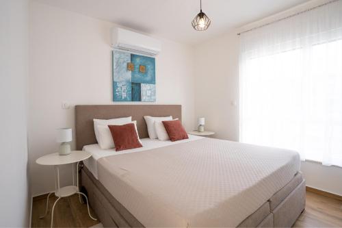 a white bedroom with a large bed and a window at Holiday House Maze with jacuzzi in Novalja