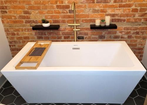 a white bath tub in front of a brick wall at Spacious luxury apt in Historic Downtown - OH Amish country in Millersburg