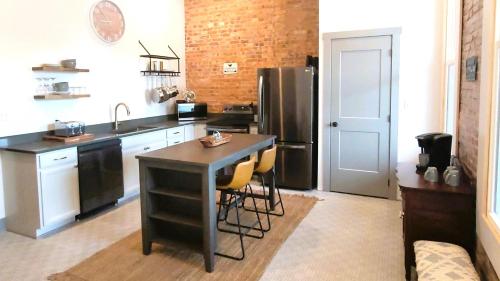 a kitchen with a table and a stainless steel refrigerator at Spacious luxury apt in Historic Downtown - OH Amish country in Millersburg