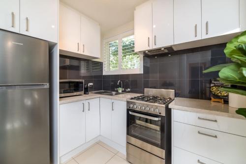 a kitchen with white cabinets and a stainless steel refrigerator at Cosy and convenient leafy apartment 