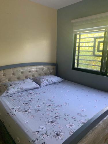 a bedroom with a bed with a blue comforter and a window at Cagayan De Oro house in Cagayan de Oro