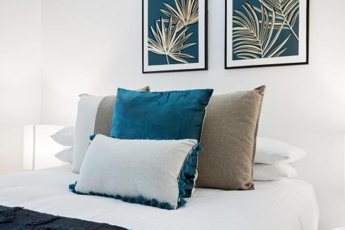 a white bed with pillows on top of it at Comfy 2-Bed with Pool and Secure Parking in Brisbane