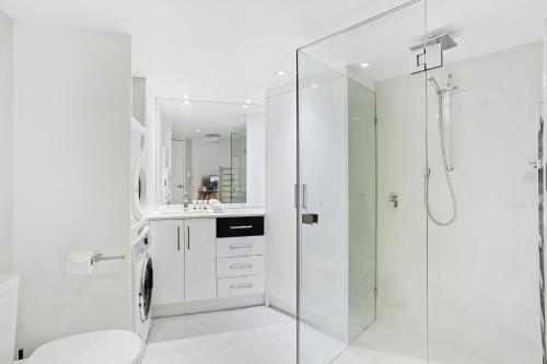a white bathroom with a shower and a toilet at Comfy 2-Bed with Pool and Secure Parking in Brisbane