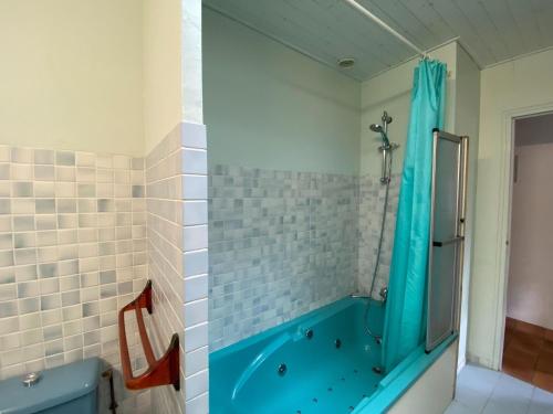 La salle de bains est pourvue d'une douche et d'une baignoire bleue. dans l'établissement Holiday Home in Vendee near Sandy Beaches, à Les Sables-dʼOlonne